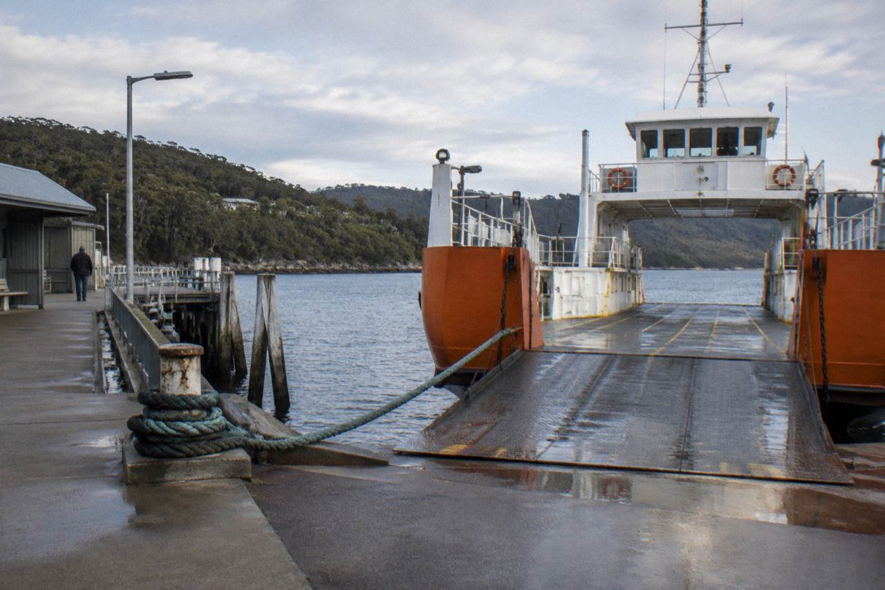 A vehicle ferry loading at a small terminal wharf on a calm morning