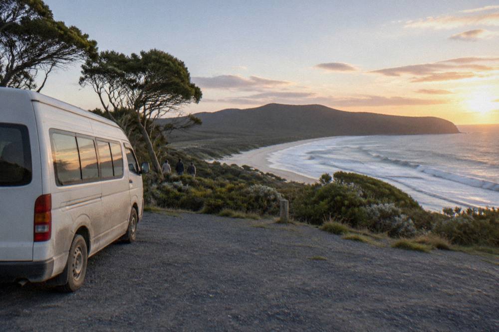 A small group minibus parked at a coastal lookout on Bruny Island