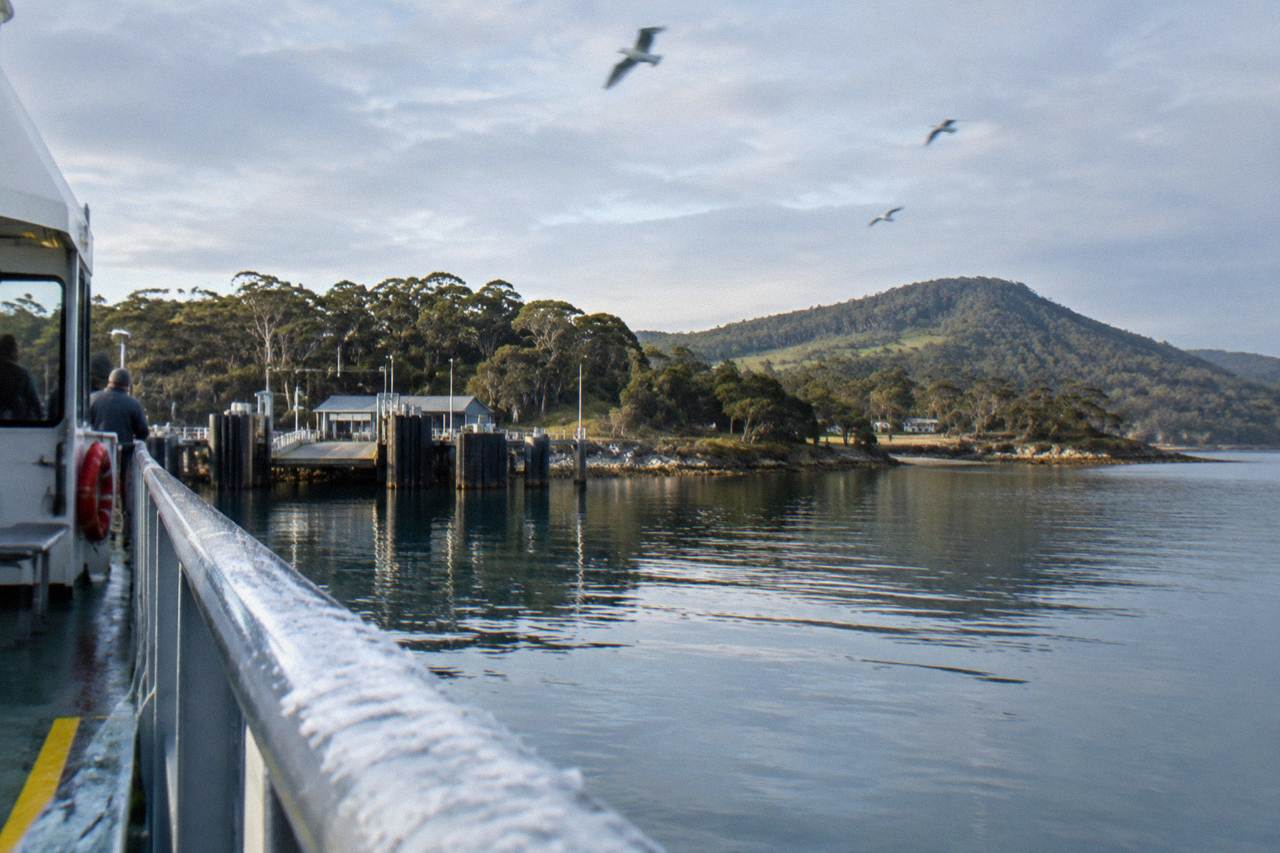 A calm water view from the Bruny Island ferry looking toward the island's green hills