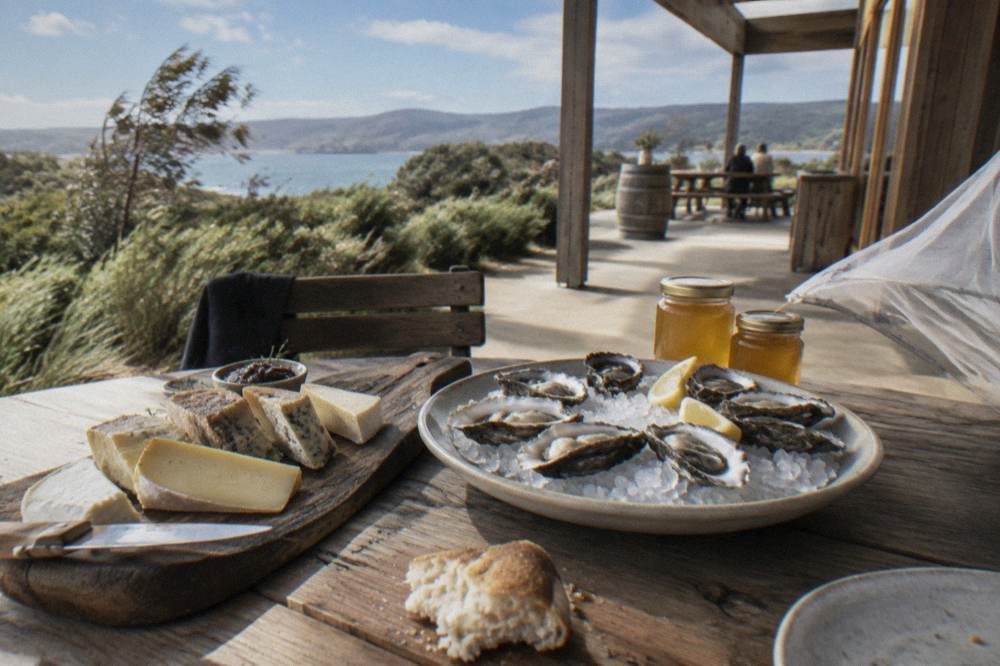 Ploughed cheese board with oysters and honey jars on a wooden tasting table