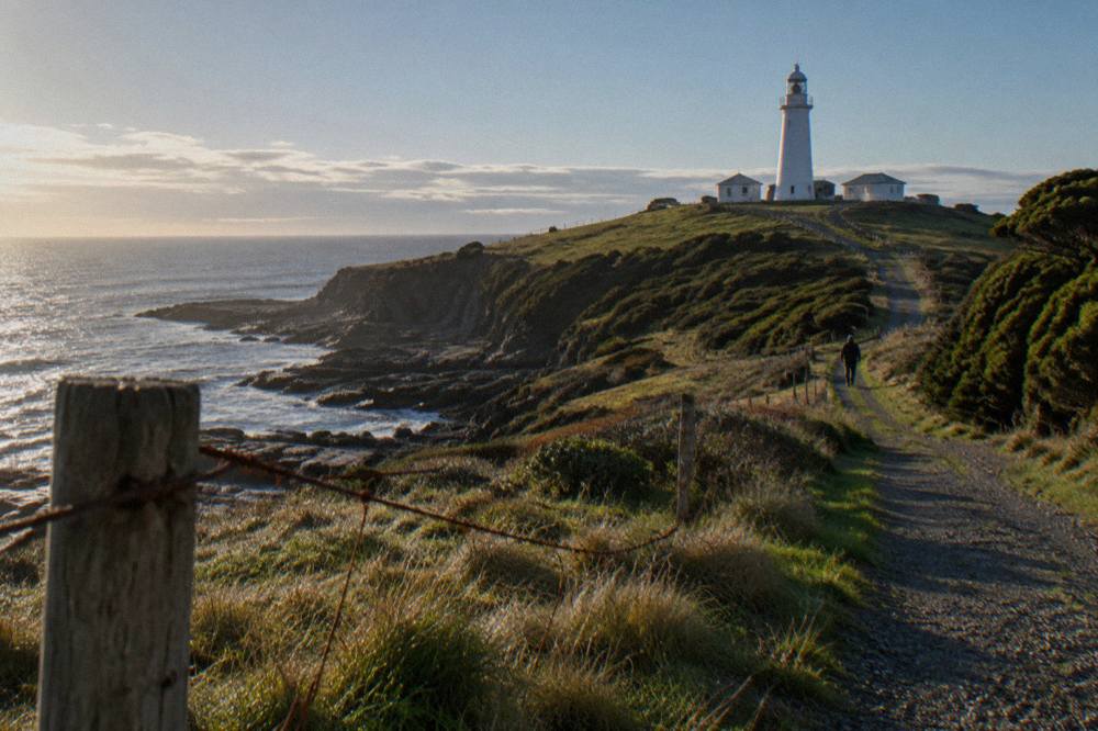 The white Cape Bruny Lighthouse standing on a green headland above the Southern Ocean