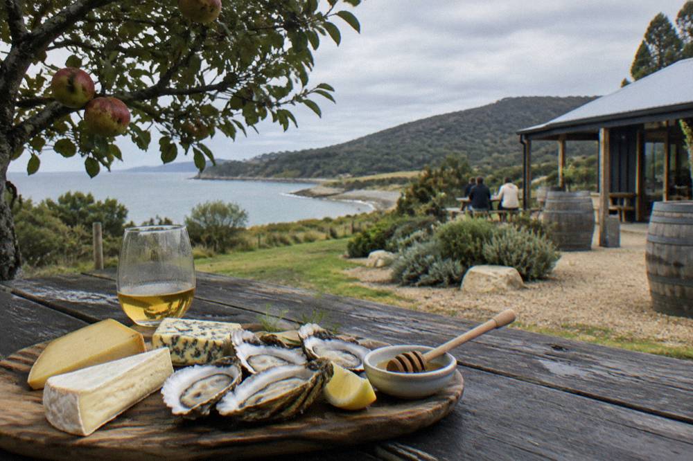 A tasting platter of cheese, oysters and honey on a timber table at a Bruny Island cellar door