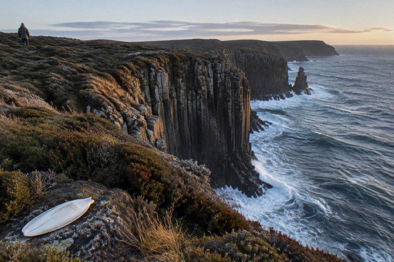 Open ocean swell breaking against tall dolerite sea cliffs on a rugged island coastline