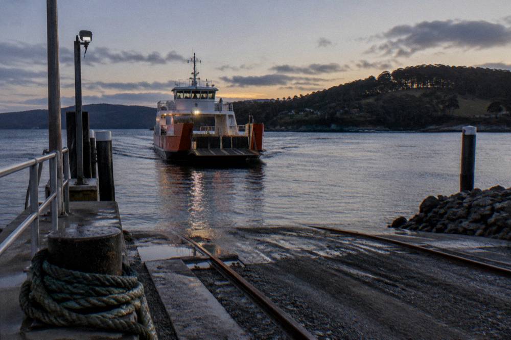 Vehicle ferry approaching a ramp terminal across calm water