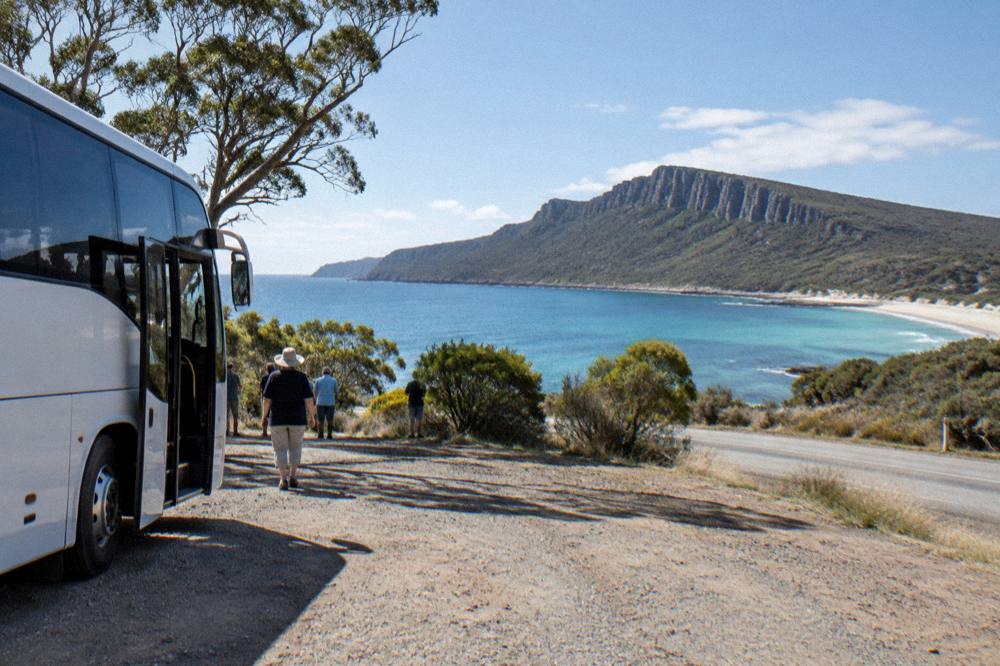 Coach parked beside a coastal road with a view over a bay and headland