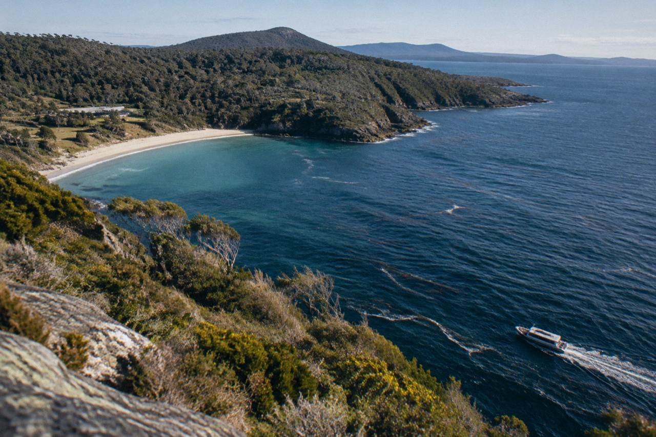 Open cruise boat passing tall dolerite sea cliffs along the Bruny Island coastline