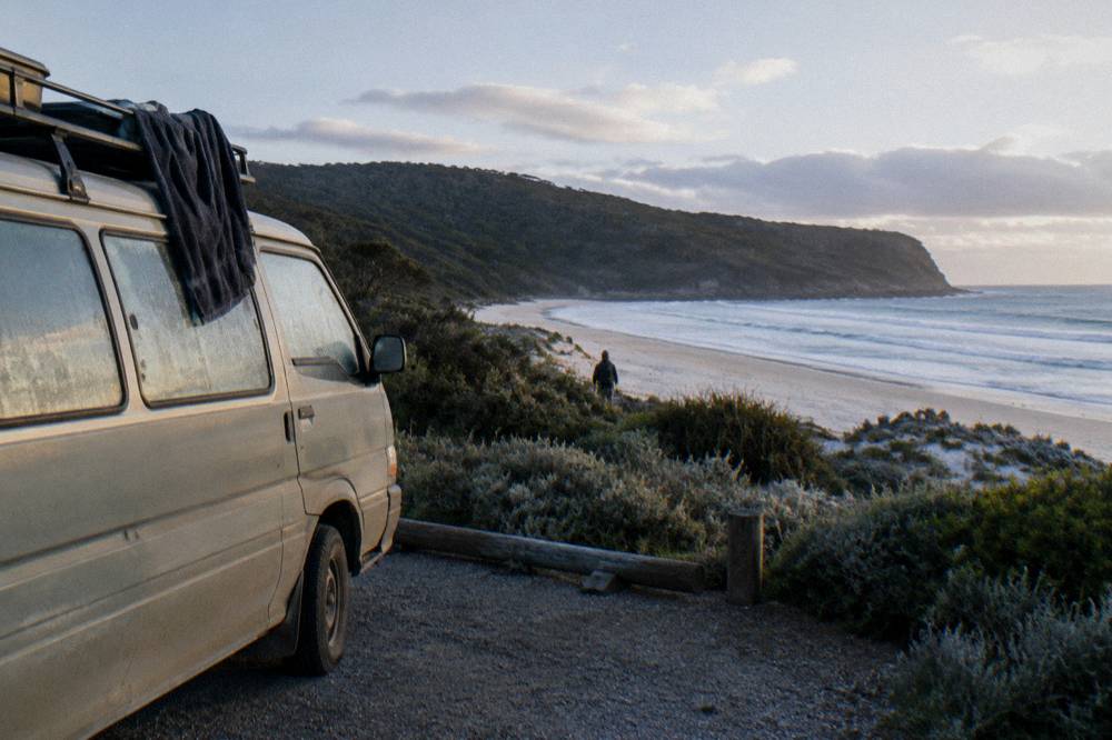 Campervan parked at a beachside campground near low coastal scrub