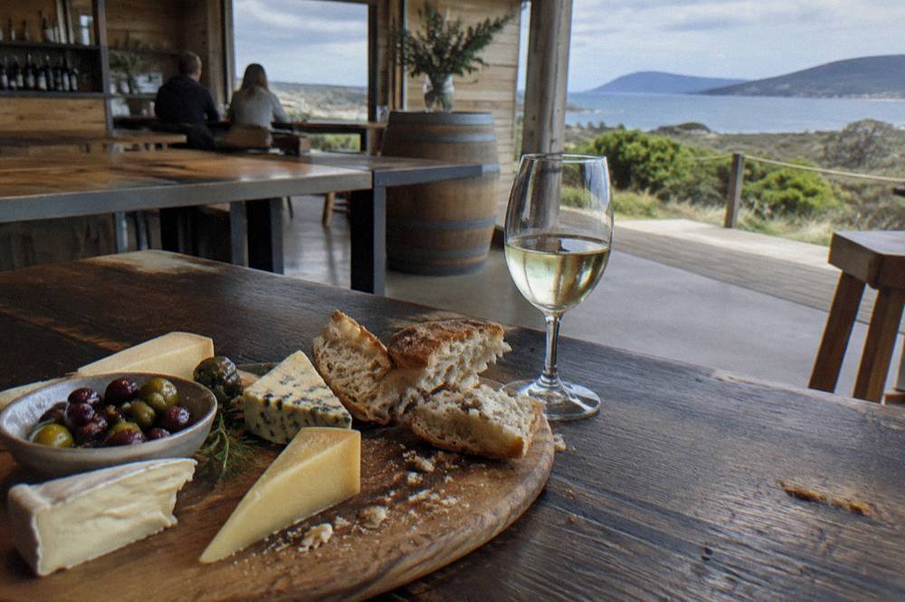 A cellar door tasting platter with cheese, olives and bread beside a glass of white wine