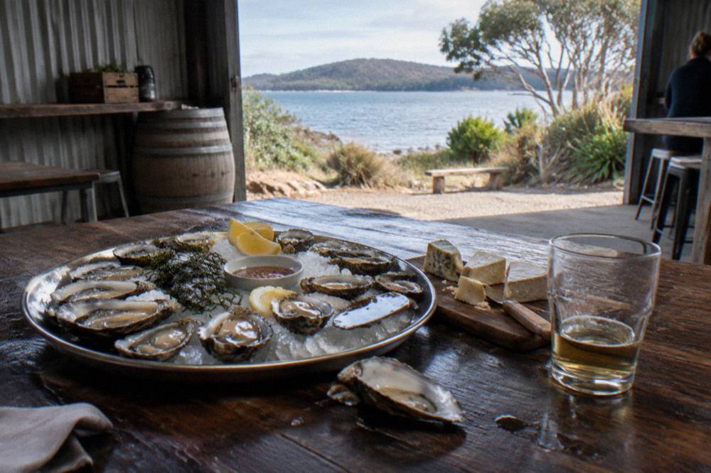 A platter of oysters and local cheese on a timber table at a Bruny Island producer