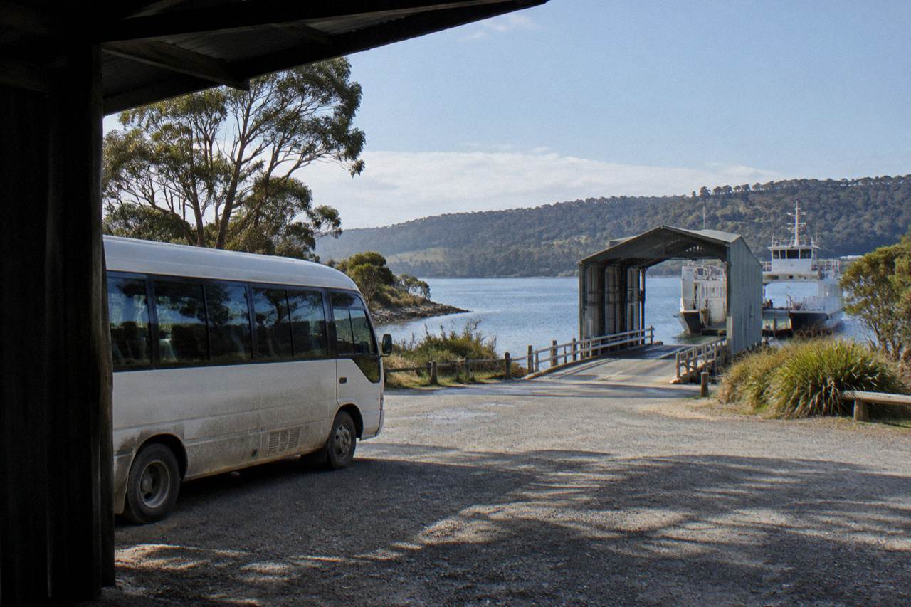 A tour minibus parked beside the Kettering ferry terminal on a bright morning in southern Tasmania