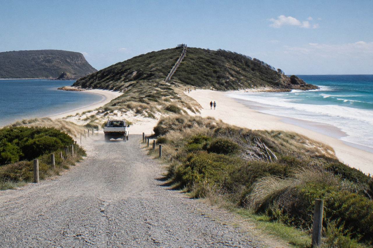 View from a lookout over the sandy spit of The Neck connecting north and south Bruny Island under a wide sky