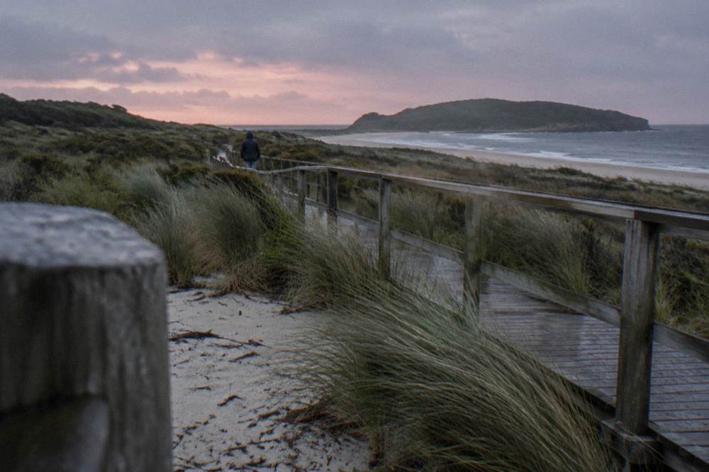A dusk sky fading over coastal dunes and a timber boardwalk, with no people on the platform